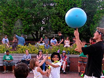 Juggler showing kids how to spin a blue ball on a stick