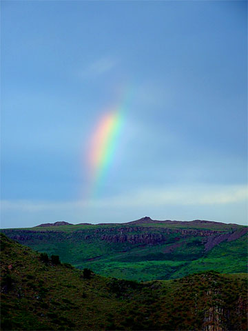 Rainbow fragment above rocky hills (superzoom)