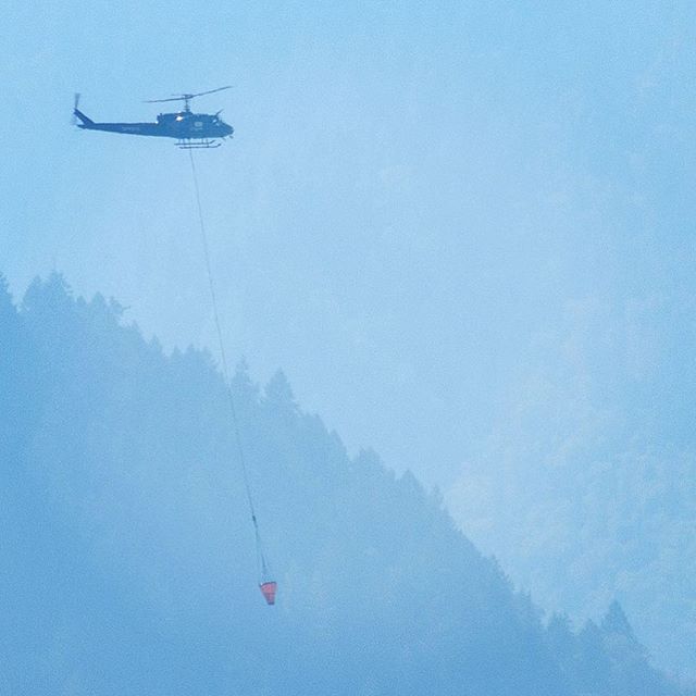 Helicopter carrying over a bucket of water to Oregon fire