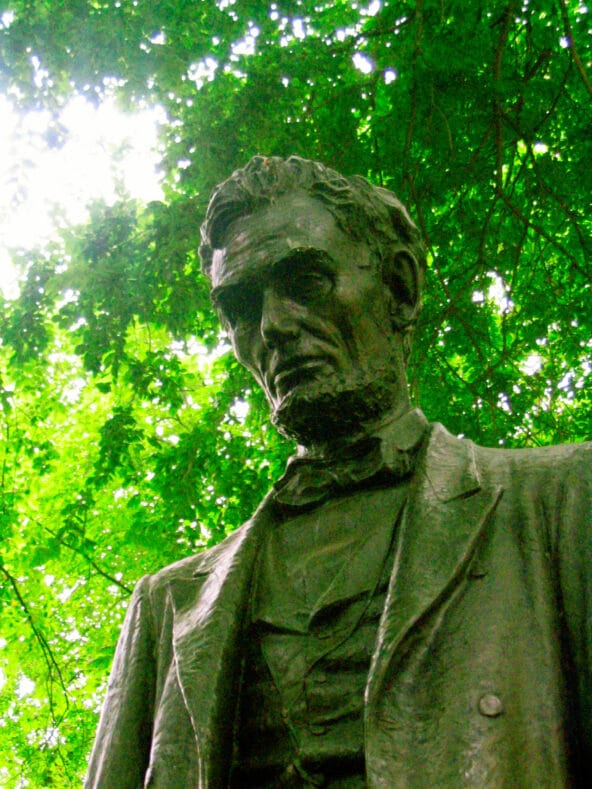 Abraham Lincoln Statue before sun and green leaves