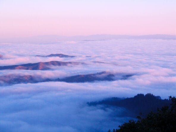 Clouds rolling over hills n Pacific Ocean zoom