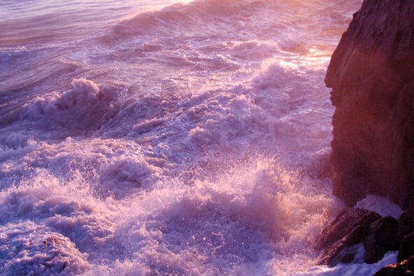 Crashing foamy waves by rocks