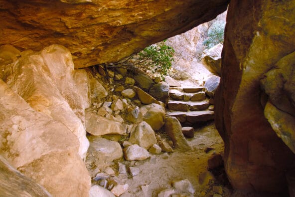 Desert path leading under boulders