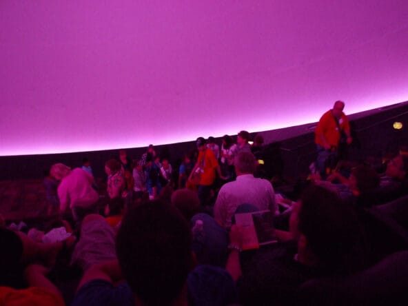 People sitting under violet IMAX screen
