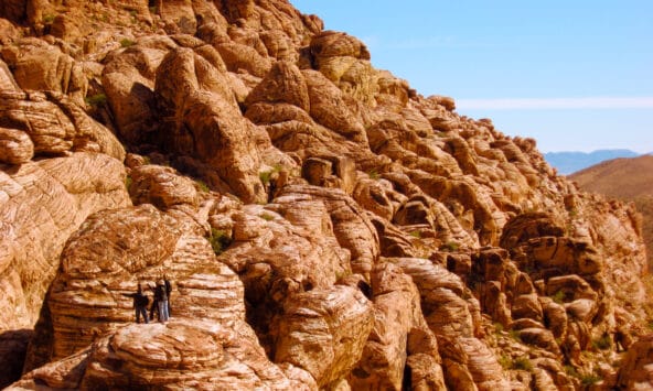 People standing on ancient red boulders along ridge