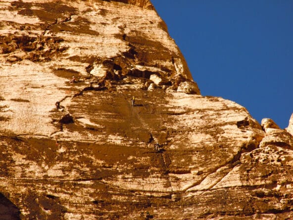 Two people scaling steep incline