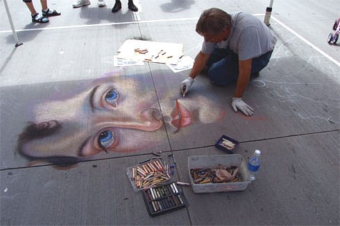Chalk artist drawing realistic face onto street