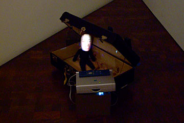 Tiny doll in a suitcase, Zero by Tony Oursler