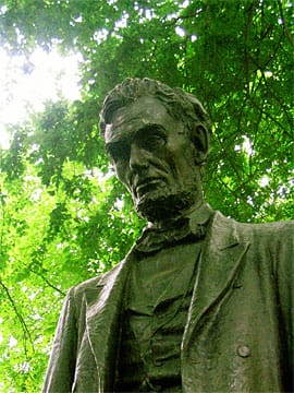 Abraham Lincoln Statue before sun and green leaves