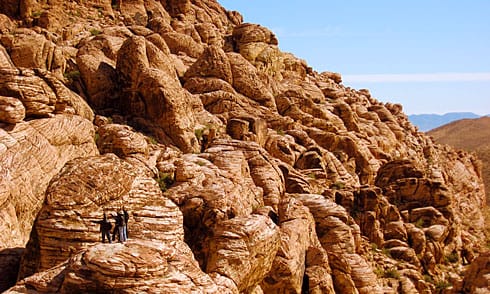 People standing on ancient red boulders along ridge